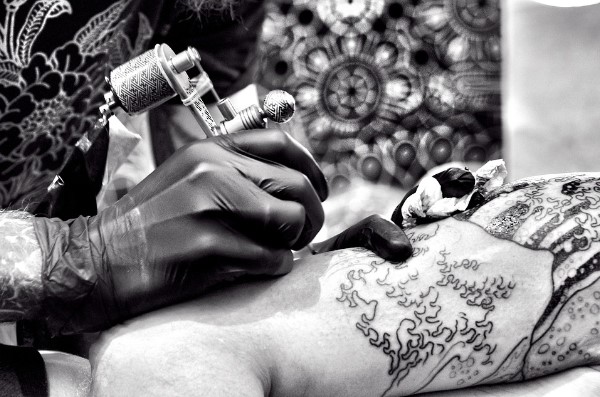 Persona tatuando brazo