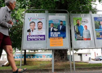 A woman walks past electoral posters of the upcoming parliamentary elections in Saint Jean de Luz, southwestern France, Wednesday June 8, 2022. The legislative elections will take place on June 12 and 19, 2022. (AP Photo/Bob Edme)