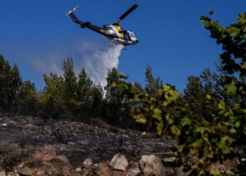A firefighting helicopter throws water as fire burns in the area of Drafi east of Athens on Wednesday, July 20, 2022. Hundreds of people were evacuated from their homes late Tuesday as a wildfire threatened mountainside suburbs northeast of Athens. F