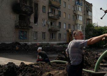 Workers drain water from a crater created by an explosion that damaged a residential building after a Russian attack in Slovyansk, Ukraine, Sunday, Aug. 28, 2022. (AP Photo/Leo Correa)