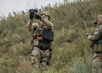 A volunteer soldier holds up a drone used to release explosives at a training area outside Kyiv, Ukraine, Saturday, Aug. 27, 2022. Some volunteers signed up to join a Chechen unit that fights alongside the Ukrainian military. Fighters from Chechnya,
