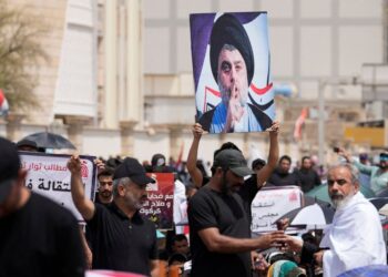 Supporters of Shiite cleric Muqtada al-Sadr with his poster gather during an open-air Friday prayers near the parliament building in Baghdad, Iraq, Friday, Aug. 26, 2022. Al-Sadr's supporters continue their sit-in outside the parliament to demand ear