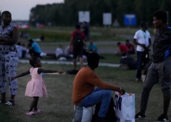 Hundreds of migrants who seek shelter prepare to spend the night outside an overcrowded asylum seekers center in Ter Apel, northern Netherlands, Thursday, Aug. 25, 2022. (AP Photo/Peter Dejong)