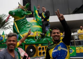 An impersonator of Brazilian President Jair Bolsonaro rides a cow statue during a campaign event for Bolsonaro's run for reelection in Duque de Caxias, on the outskirts of Rio de Janeiro, Brazil, Friday, Oct. 14, 2022. The presidential run-off electi