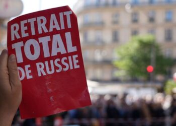 FILE - An environmental activist holds a poster reading "Total Withdrawal from Russia" outside a building hosting TotalEnergies annual shareholders' meeting, Wednesday, May 25, 2022 in Paris. A French and a Ukrainian NGOs have filed a complaint for "