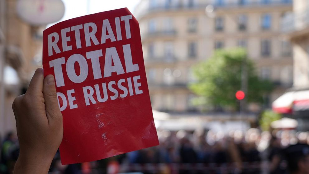FILE - An environmental activist holds a poster reading "Total Withdrawal from Russia" outside a building hosting TotalEnergies annual shareholders' meeting, Wednesday, May 25, 2022 in Paris. A French and a Ukrainian NGOs have filed a complaint for "