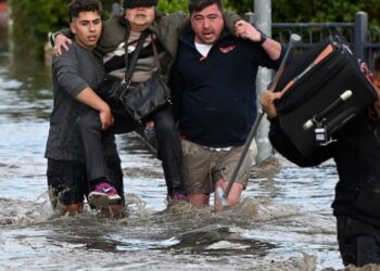 A woman is rescued from floodwater in Melbourne, Australia's suburb of Maribyrnong, Friday, Oct. 14, 2022. Rivers across Australia's most populous states, New South Wales and Victoria, and the island state of Tasmania were rising dangerously with cat